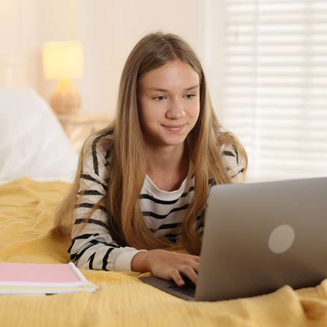 gyneka panw sto krevati me to laptop kanei online mathimata agglikwn